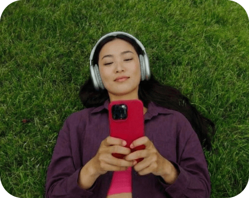 woman lying down on grass, looking at phone